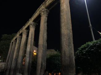 Close-up of decorative stone columns with integrated lighting illuminating a garden pathway at dusk.
