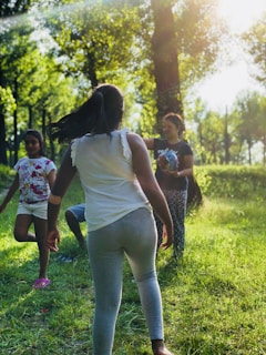 A smiling family of four enjoying a sunny day in a park with soft natural light.