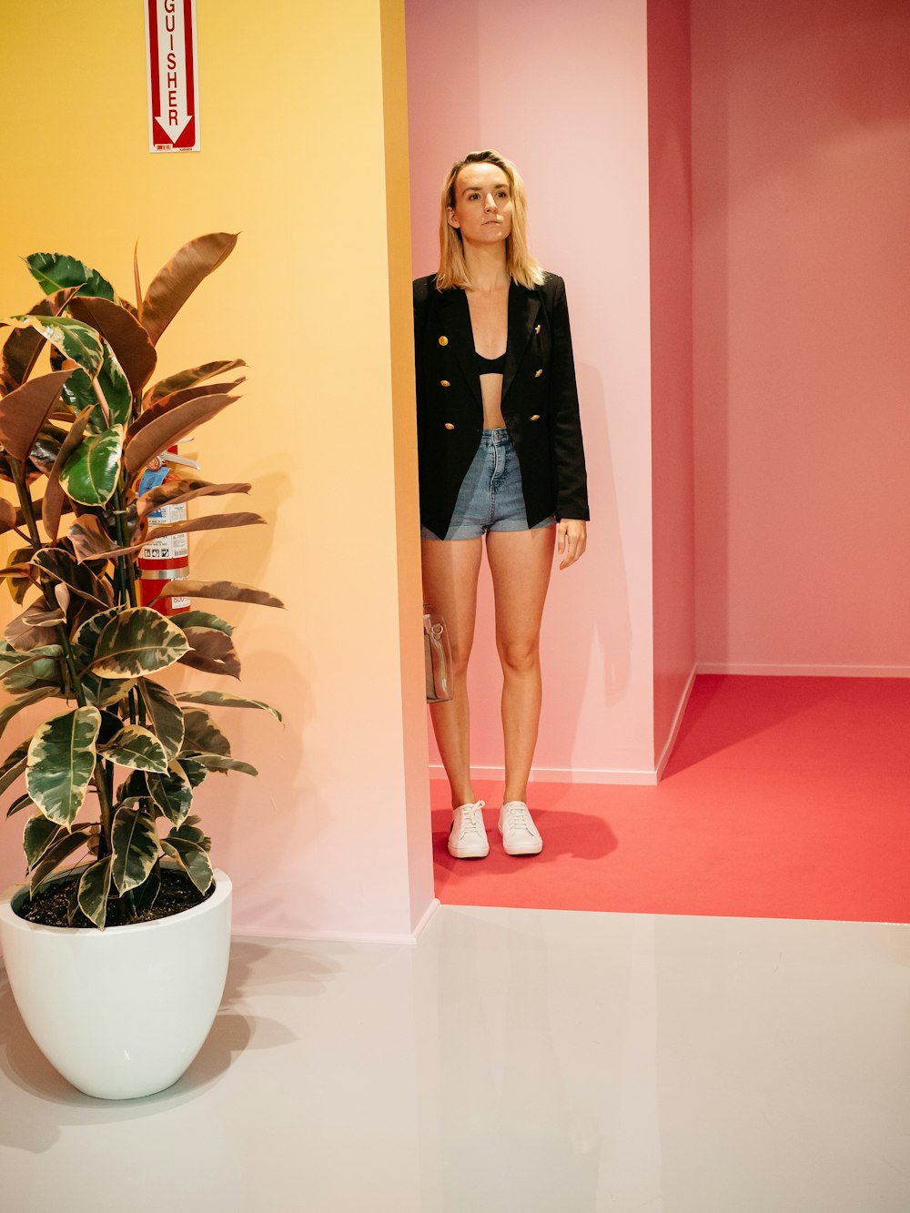 woman wearing black jacket and blue denim shorts near green-leafed plant