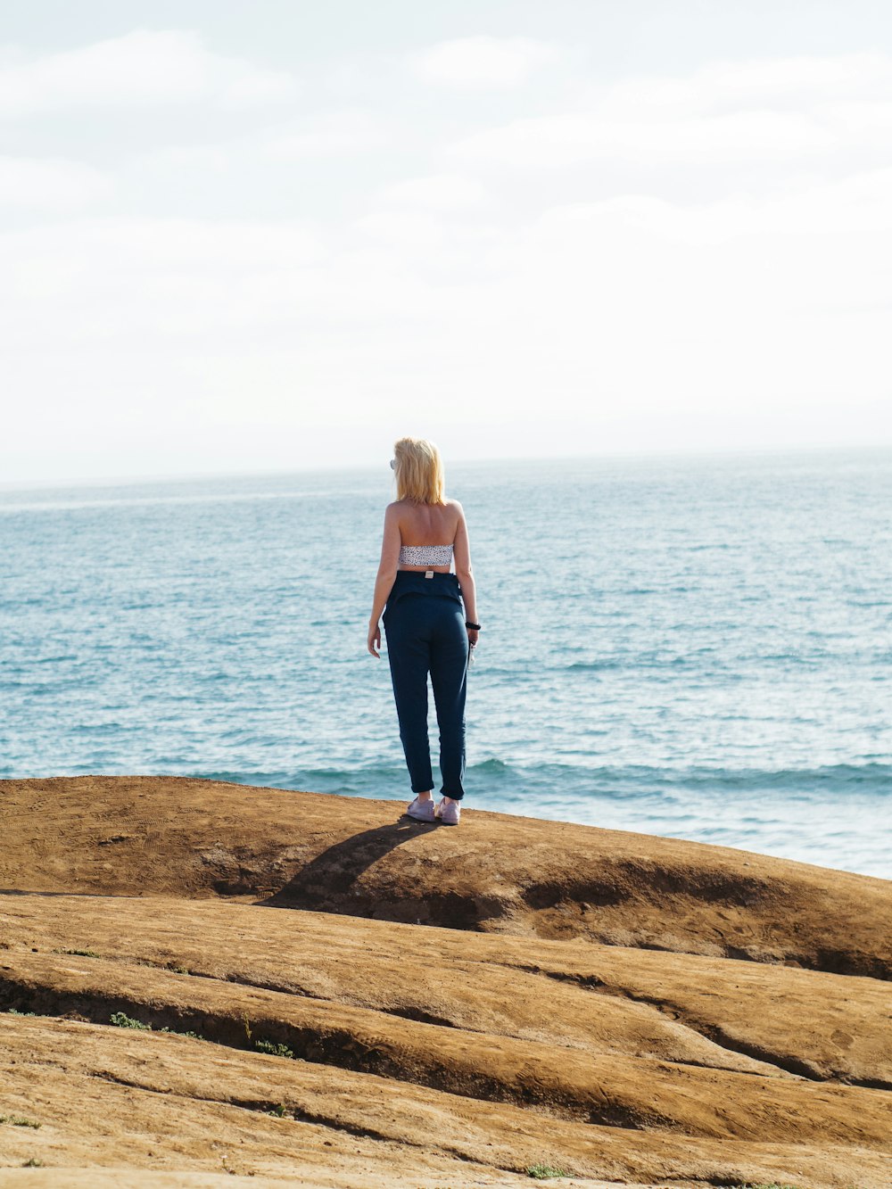 Mujer de pie sobre la roca y frente al océano durante el día