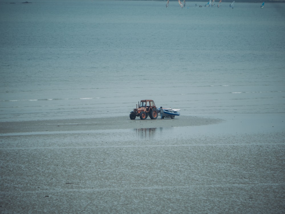 red vehicle near body of water during daytime