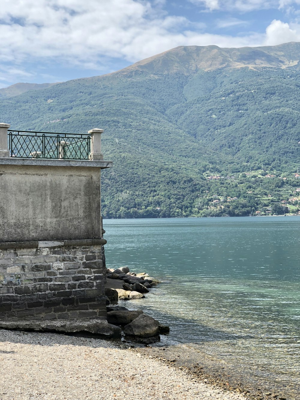 a clock tower sitting on top of a stone wall next to a body of water