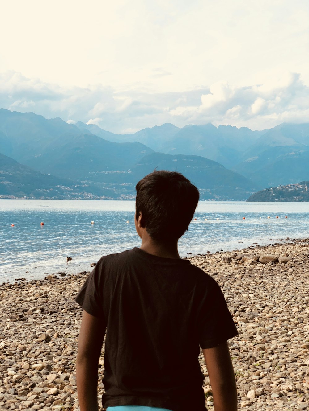 boy wearing black shirt standing on seashore