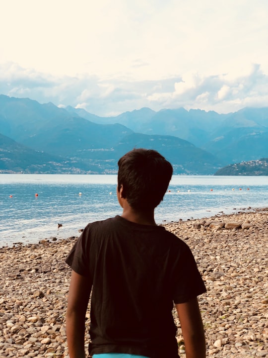 boy wearing black shirt standing on seashore in Orrido di Bellano Italy