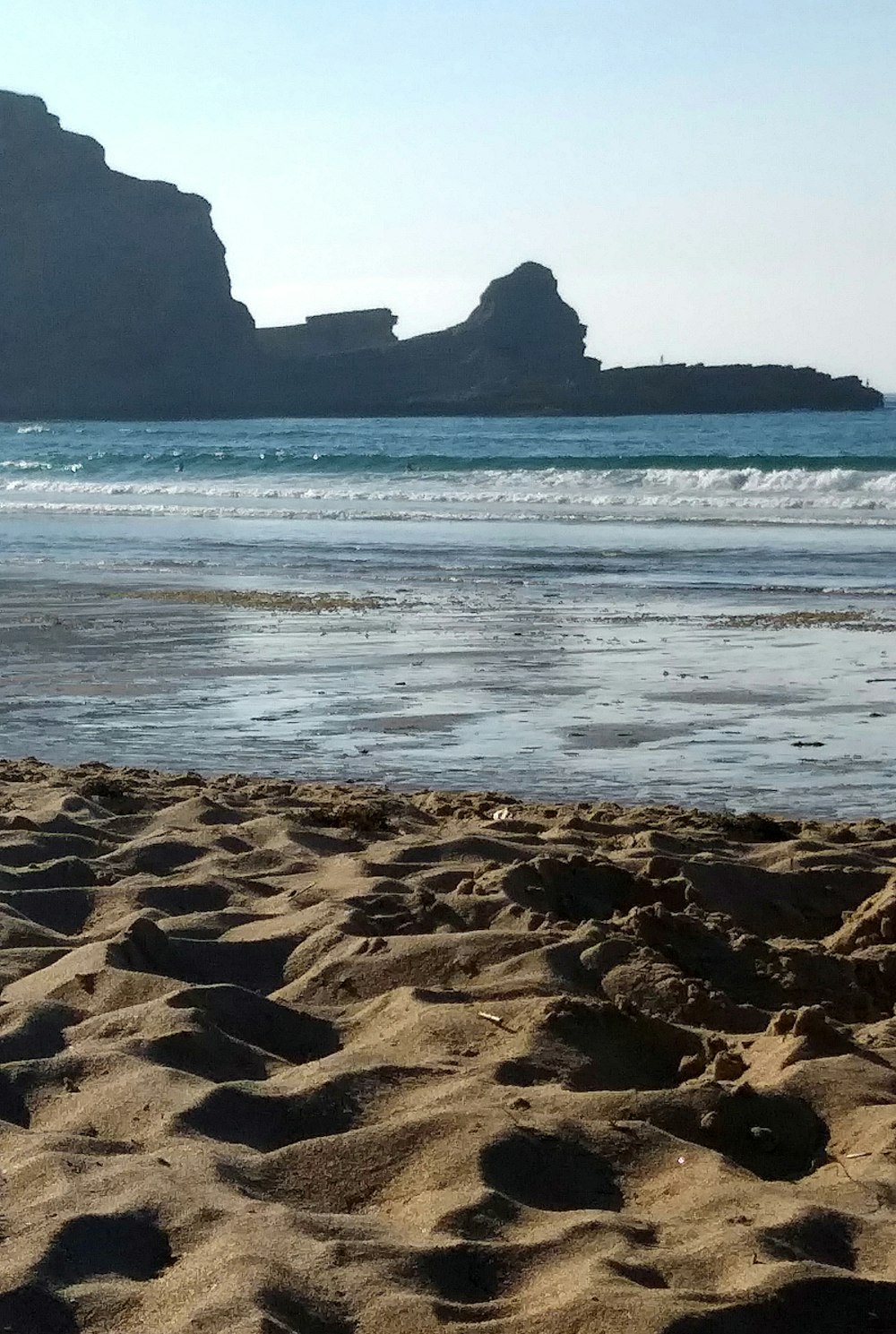 brown sand near seashore and rocks