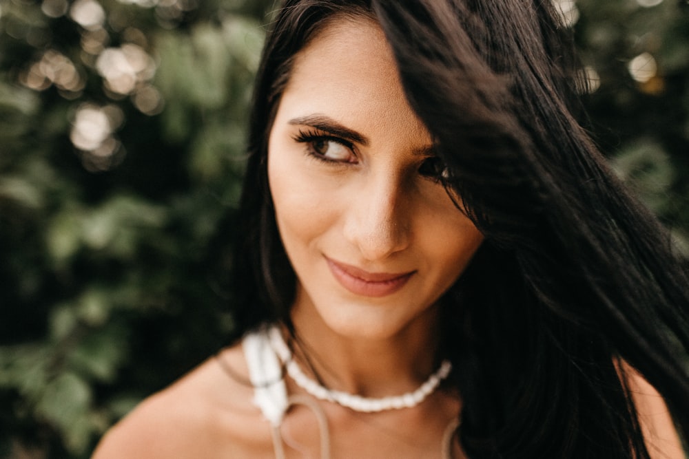 close-up photo of woman wearing white beaded necklace