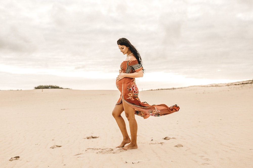 mulher segurando seu ventre em pé na praia