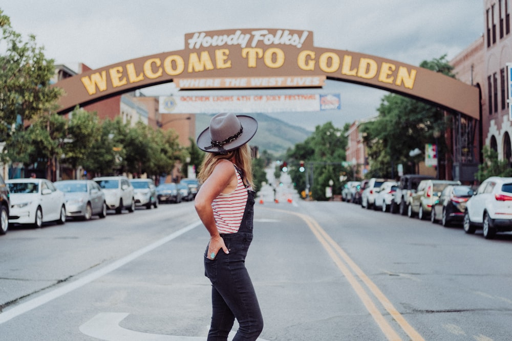 a woman standing on a skateboard in front of a welcome to golden sign