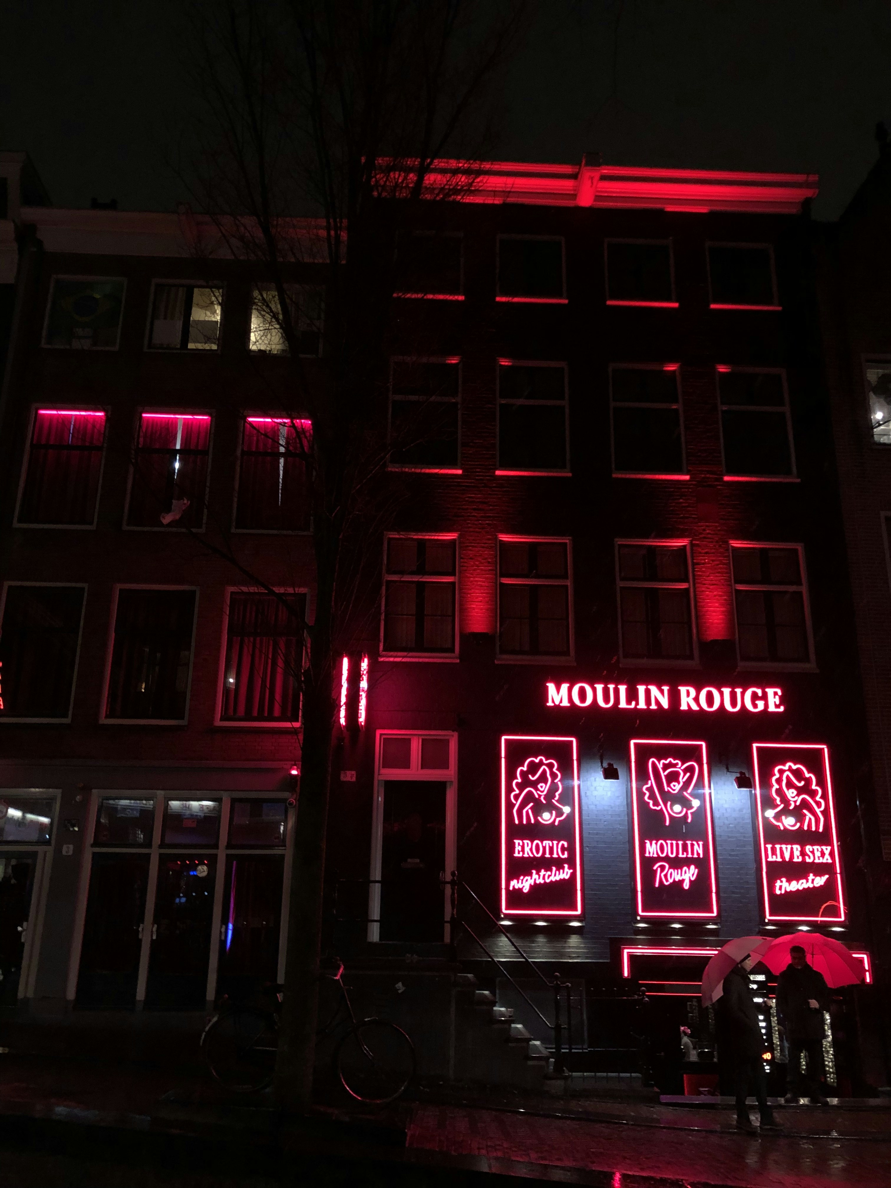two men standing and holding umbrellas beside lighted building