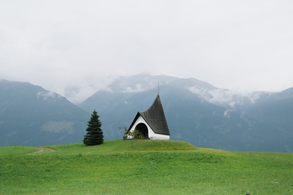 une petite église sur une colline herbeuse avec des montagnes en arrière-plan