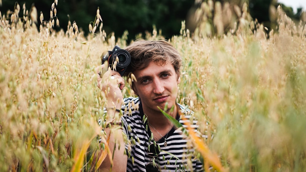 man holding black camera in field during daytime