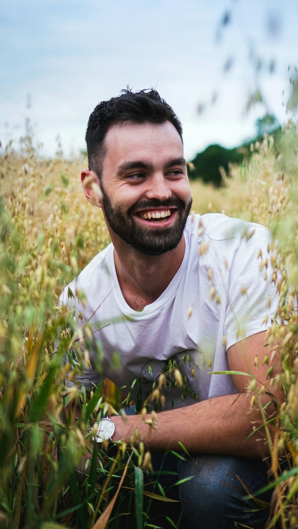 smiling man sitting surrounded by green-and-yellow plante