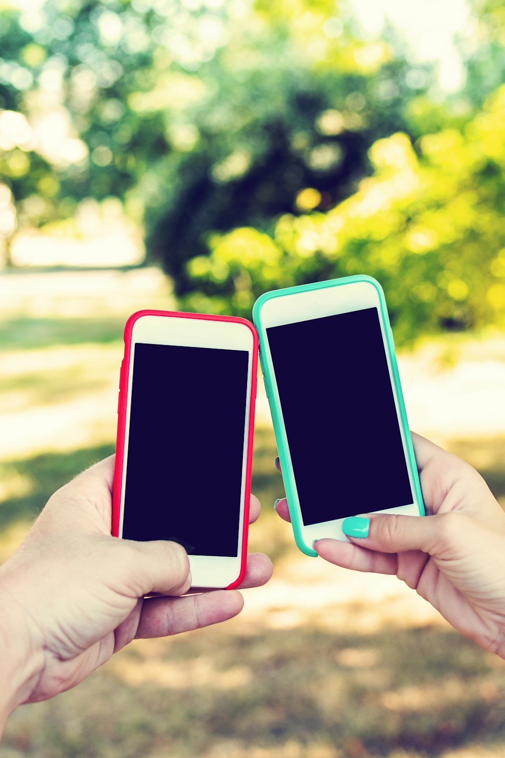 two people holding up smart phones in their hands