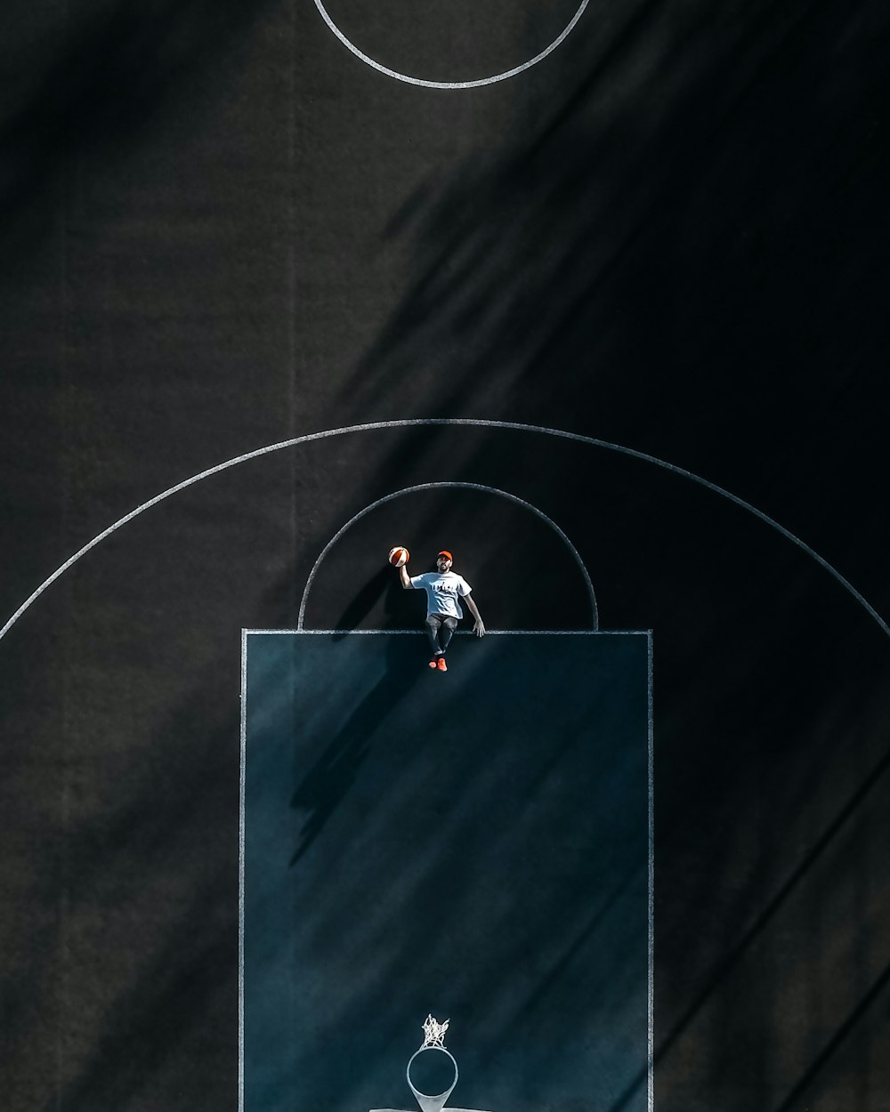 person in white t-shirt lying on basketball court