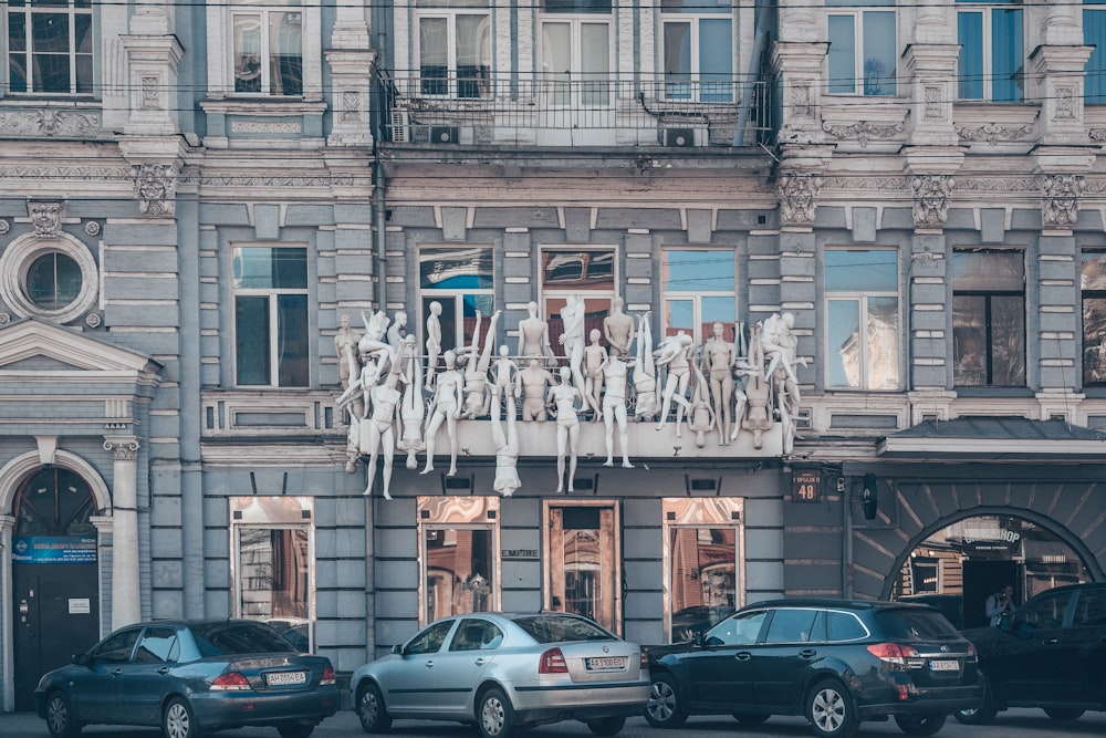 vehicles park in front building with statues at the window