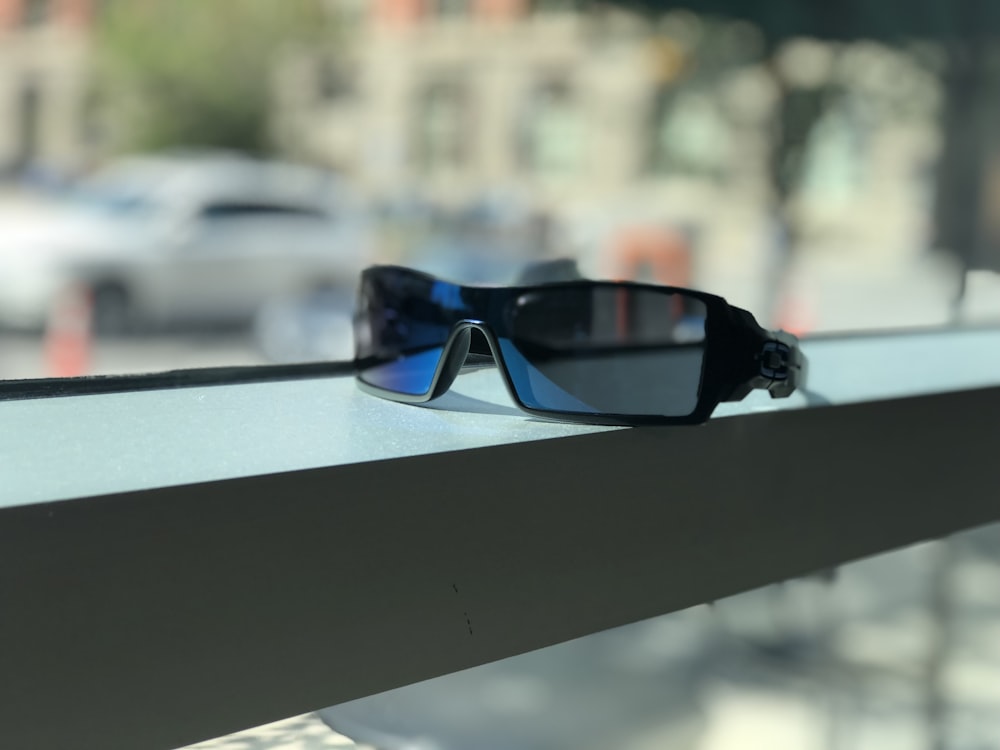 Sonnenbrille mit schwarzem Rahmen und blauem Glas in der Nähe des Fensters