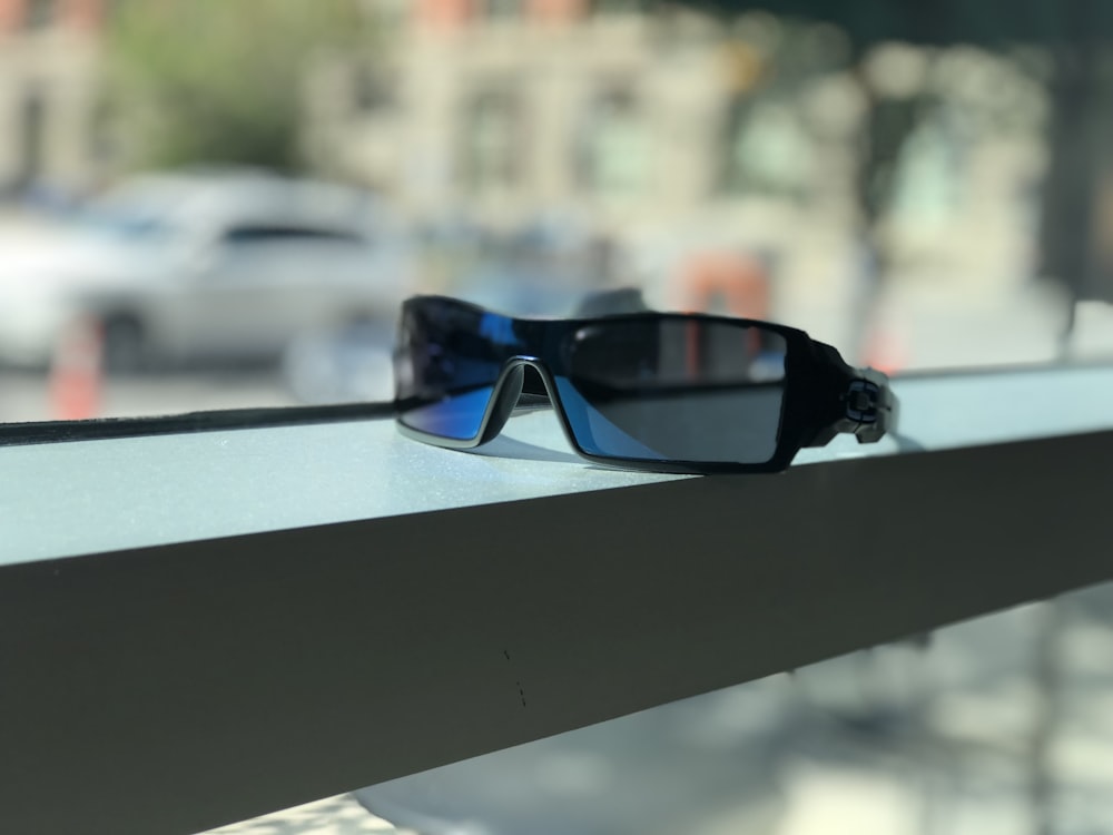 black framed blue lens sunglasses near window