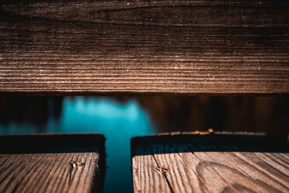 a close up of a wooden bench with water in the background