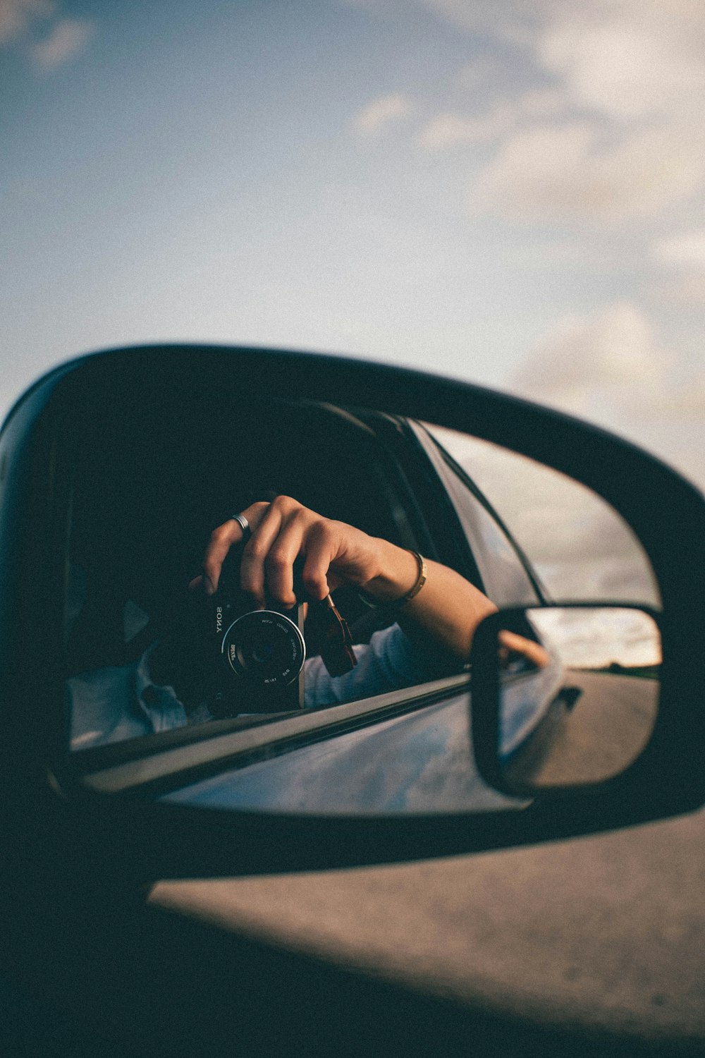 person using camera at the side mirror
