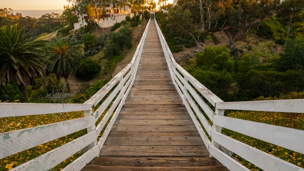 a wooden bridge with white railings leading to a beach