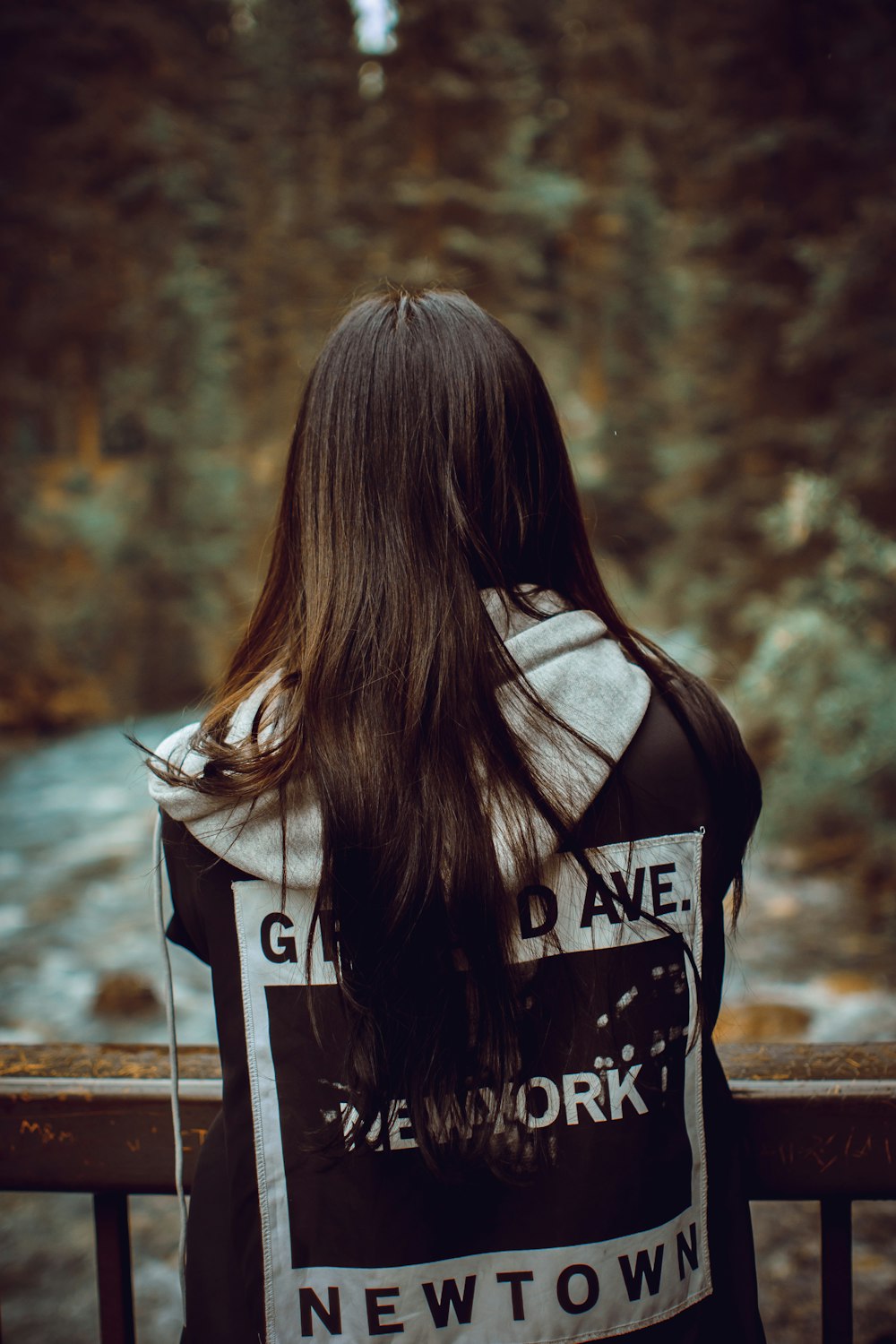 a woman standing on a bridge looking at a river