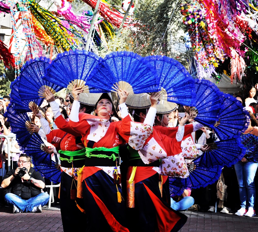 group of people dancing and holding blue hand fans during daytime