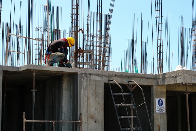 man kneeling on unfinished building during daytime