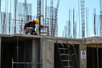 man kneeling on unfinished building during daytime