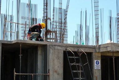 man kneeling on unfinished building during daytime