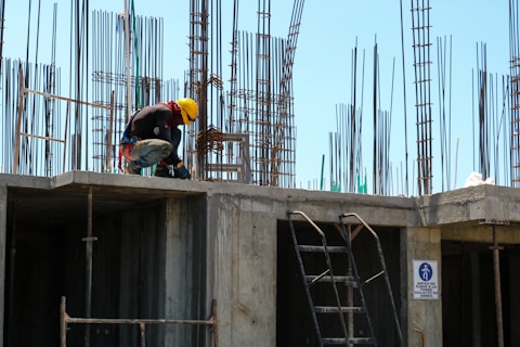 man kneeling on unfinished building during daytime