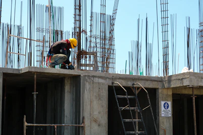 man kneeling on unfinished building during daytime