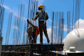 A consultant demonstrating safety measures to workers at an industrial site with clear blue sky.