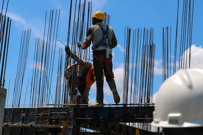 Construction workers from mh expro services wearing safety gear while working on a building site under clear skies.
