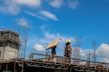 Workers handling large timber beams at a construction site.