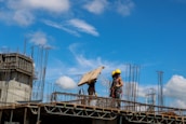 Workers handling wooden beams at a construction site.