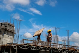 Workers handling wooden beams at a construction site.