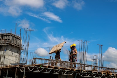 Workers handling large timber beams at a construction site.