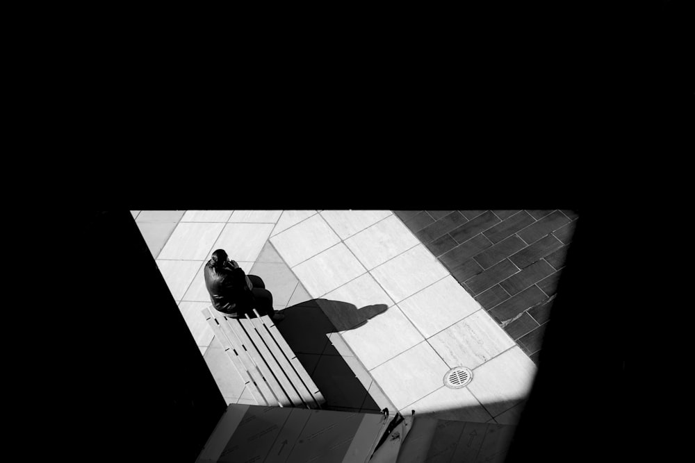 a black and white photo of a person sitting on a bench