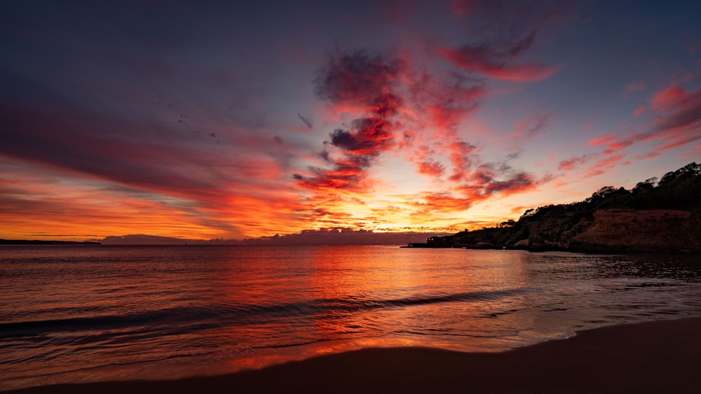 a beautiful sunset over the ocean with clouds in the sky