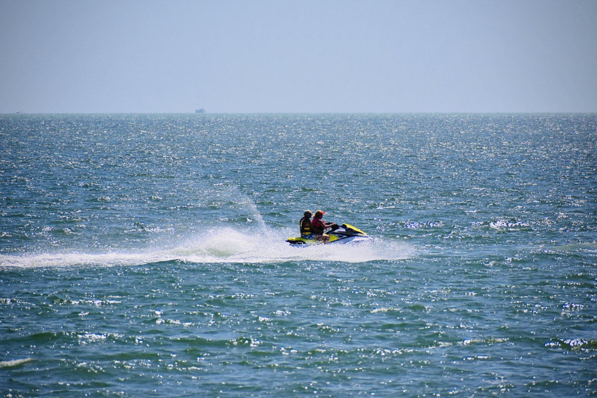 Two riders on a jet ski throwing spray