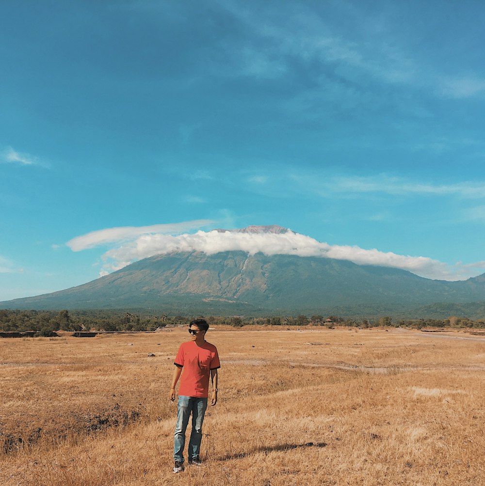 man standing on brown grass field under blue sky