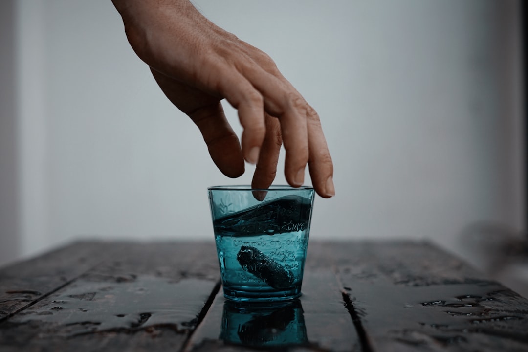 person touching teal drinking glass