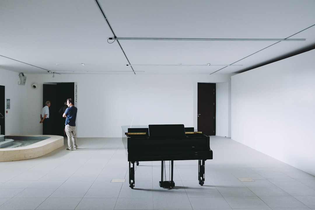 person in black T-shirt near black upright piano