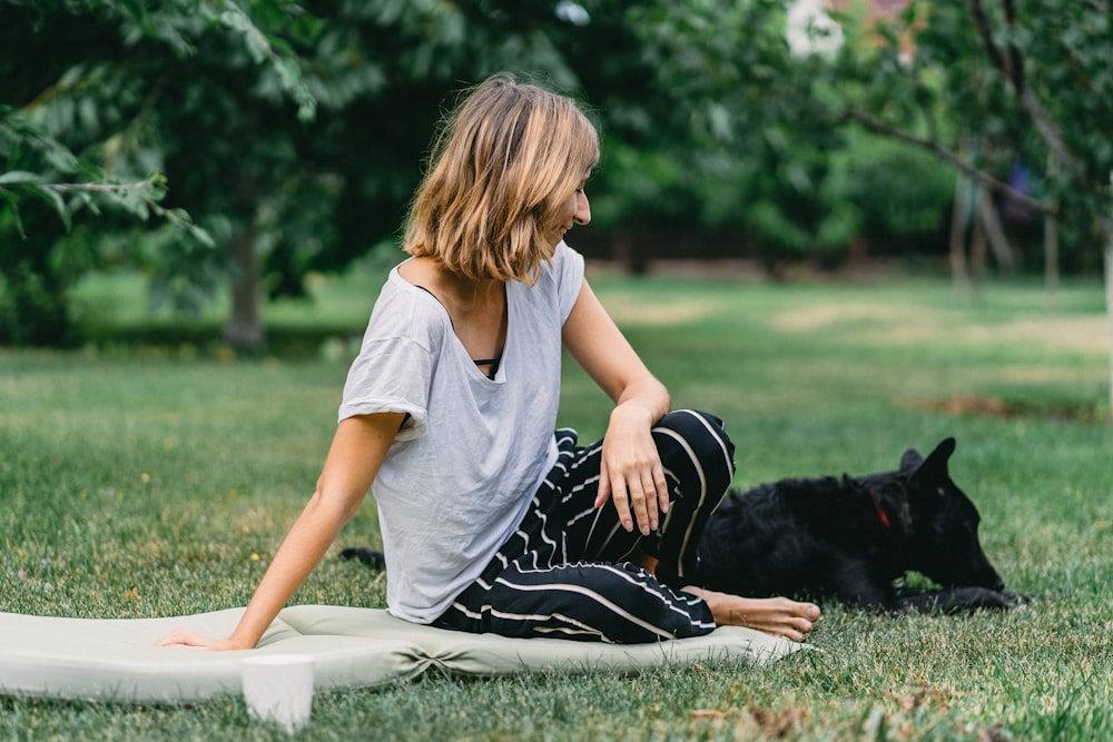 woman sitting on ground beside black dog