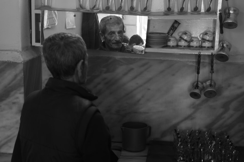 grayscale photo of man looking at mirror