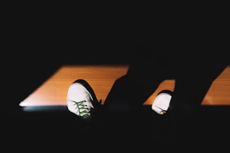 A pair of white sneakers with brightened, spotless soles illuminated by natural light.