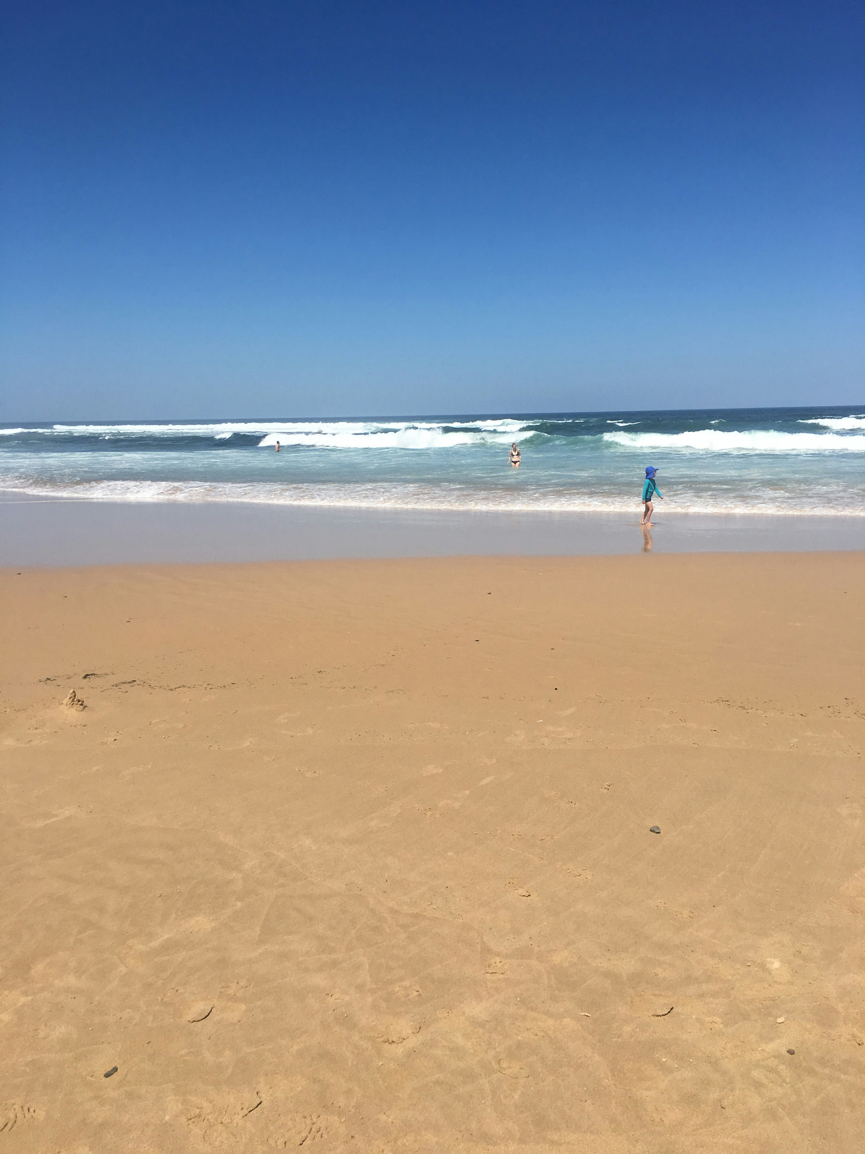 child on shore facing ocean waves