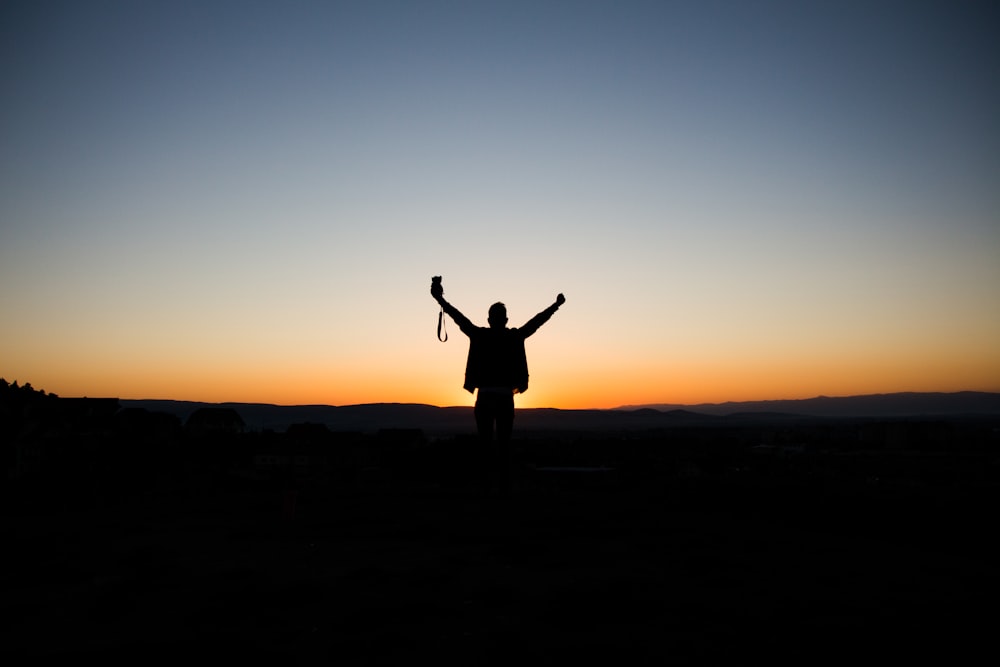 man stretching his arms silhouette at sunrise