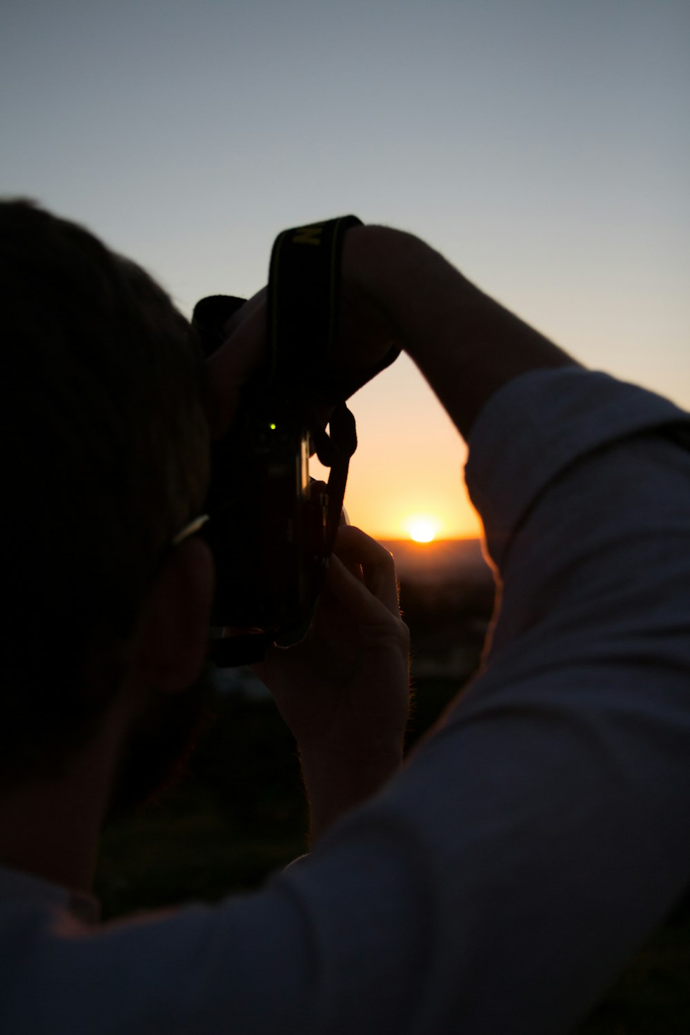 person using camera capturing sunset