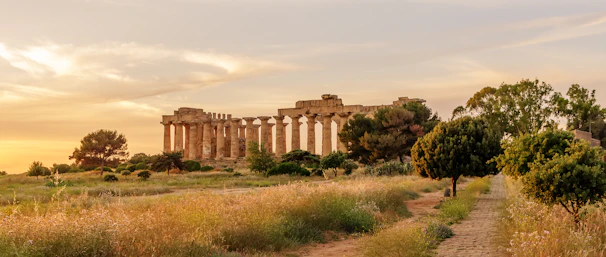 Ancient Greek temple ruins bathed in golden sunset light, evoking timeless history.